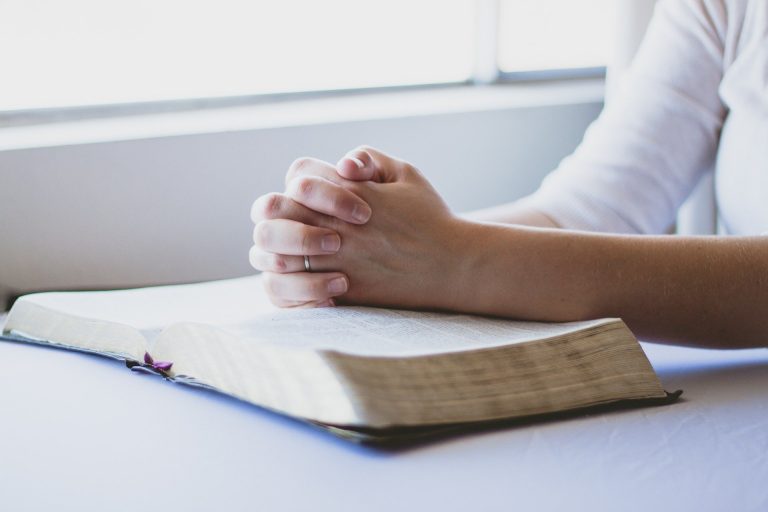 Pray, and read your Bible. Photo is woman's hands folded in prayer and resting on her Bible.