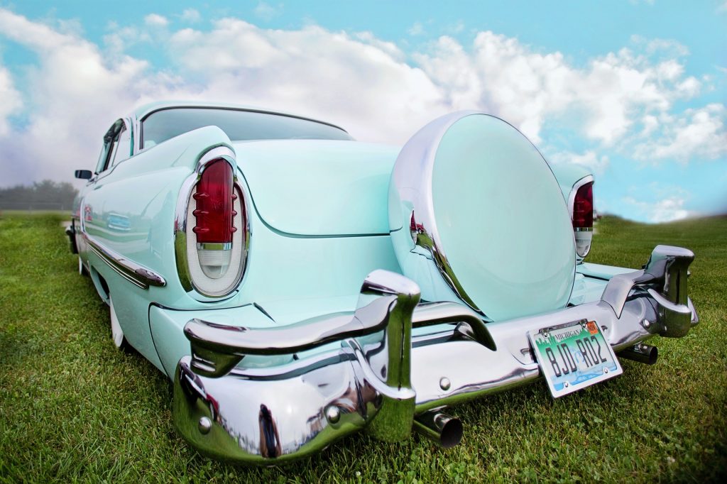 Is prayer your steering wheel or spare tire? Turquoise Vintage spare tire cover near trunk of vintage turquoise car.